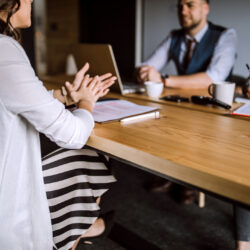Man accompanied with two women sitting in board room and having business interview